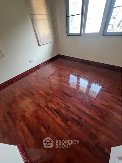 Elegant hardwood flooring in a sunlit room with large windows