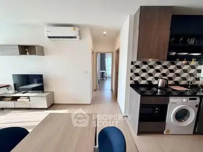 Modern open-plan living room with stylish kitchen and washing machine in a bright apartment.