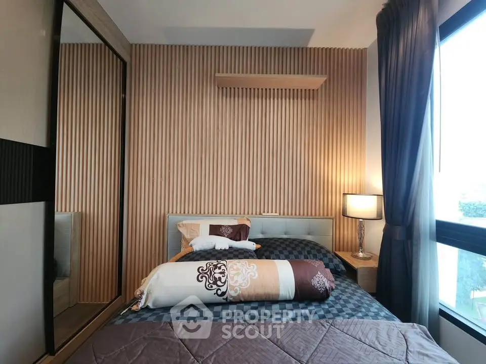 Modern bedroom with stylish decor and large window offering natural light.