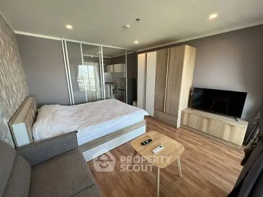 Modern studio apartment with cozy bedroom and compact kitchen area.