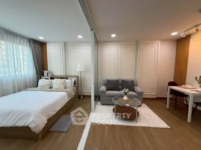 Modern studio apartment with cozy bedroom and stylish living area, featuring elegant decor and natural light.