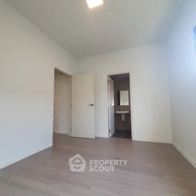 Spacious empty bedroom with ensuite bathroom and modern flooring