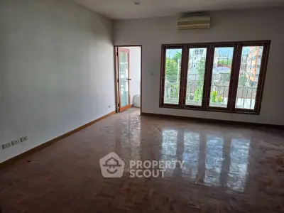 Spacious empty living room with large windows and parquet flooring