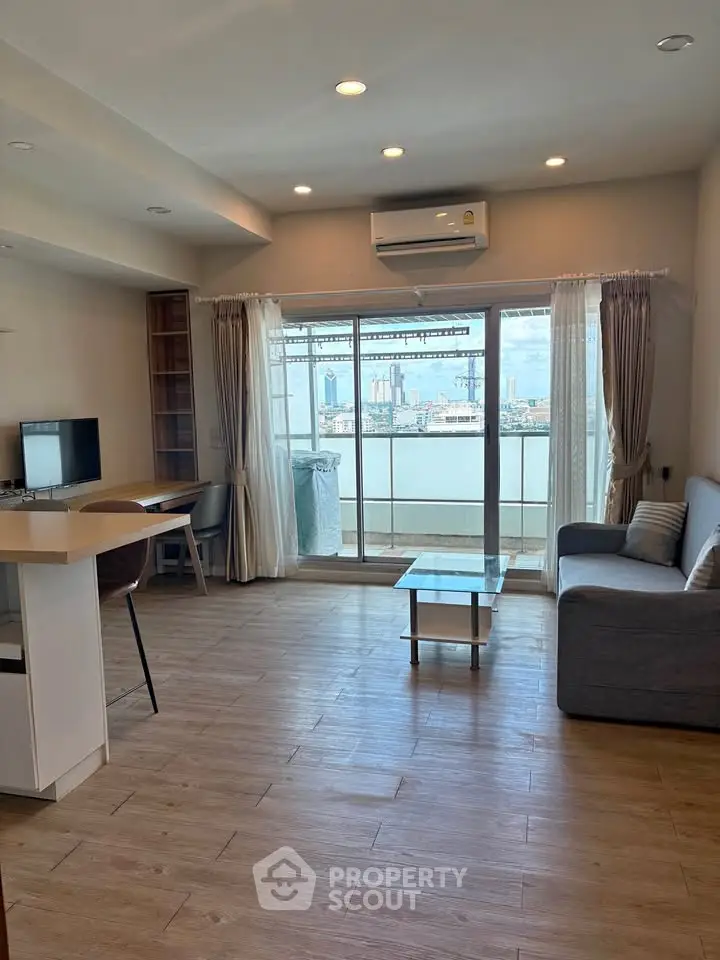 Spacious living room with city view, modern furnishings, and natural light in a high-rise apartment.