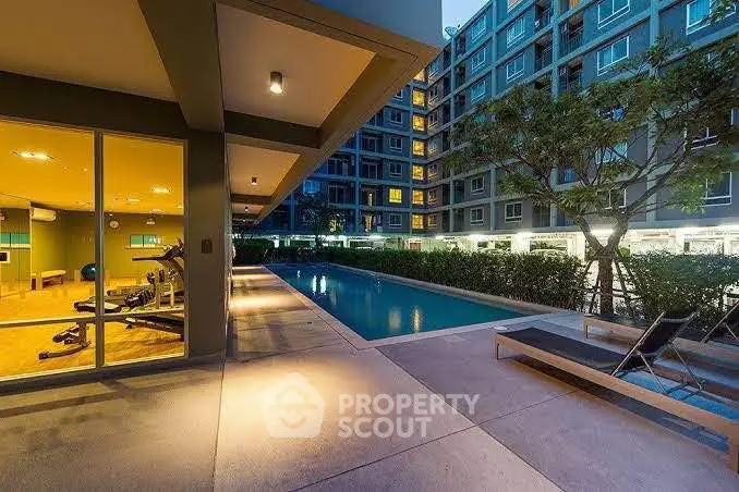 Modern apartment complex with pool and gym facilities at dusk