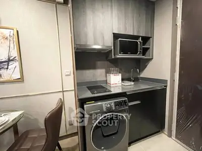 Modern compact kitchen with washing machine and microwave in sleek design.