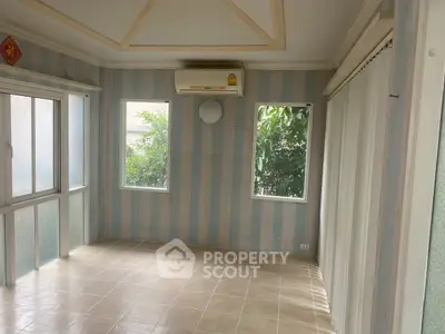 Bright room with striped walls and large windows, featuring air conditioning and tiled flooring.