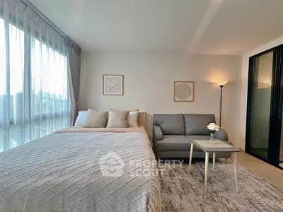 Modern bedroom with cozy seating area and large window for natural light.