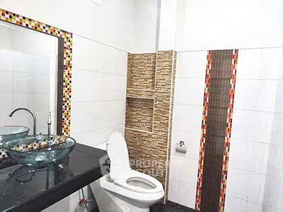 Modern bathroom with stylish glass sink and mosaic tile accents