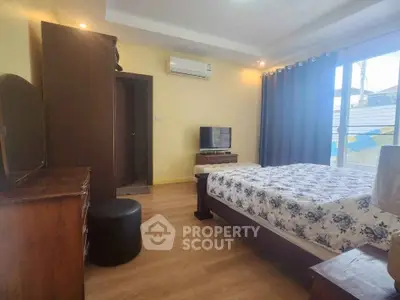 Cozy bedroom with wooden flooring and natural light, featuring a bed, TV, and air conditioning.