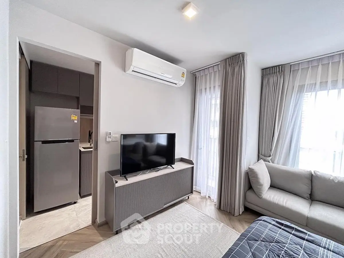 Modern living room with sleek TV setup and cozy sofa in bright apartment.