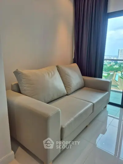 Modern living room with sleek sofa and panoramic window view in high-rise apartment.