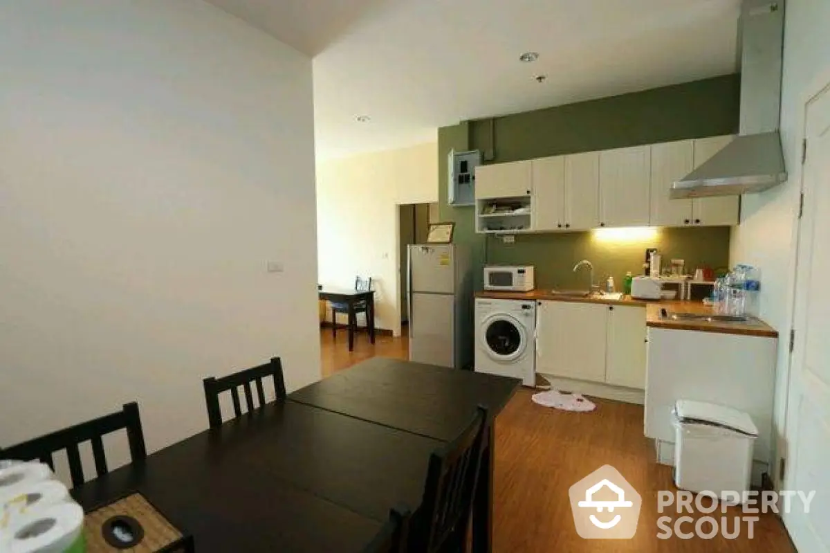 Modern kitchen with dining area, featuring washing machine and sleek appliances.