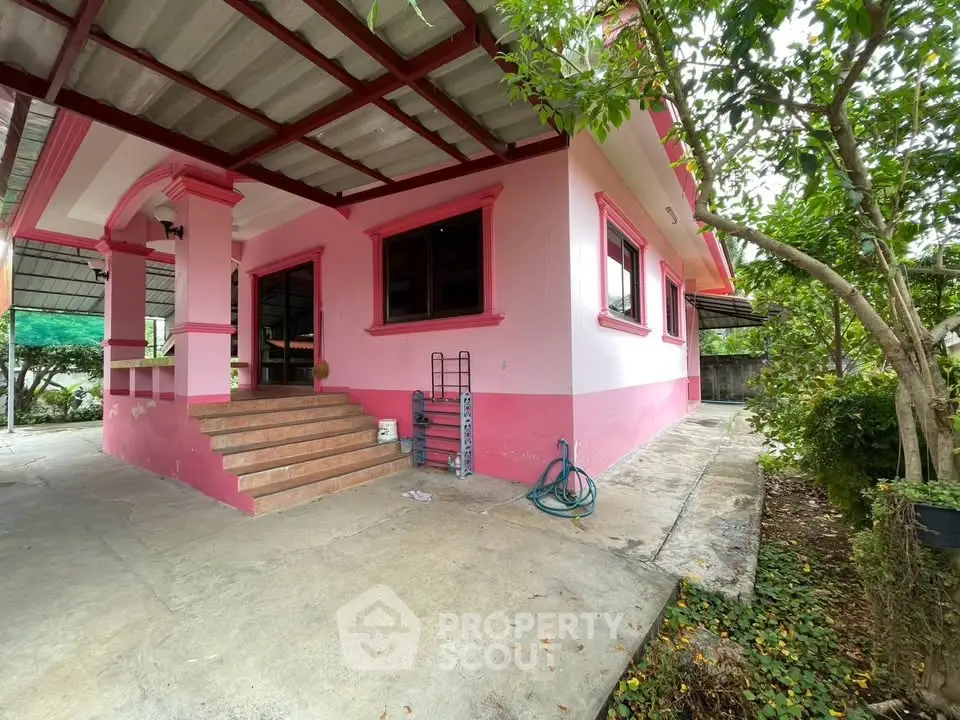 Charming pink house with lush greenery and inviting entrance