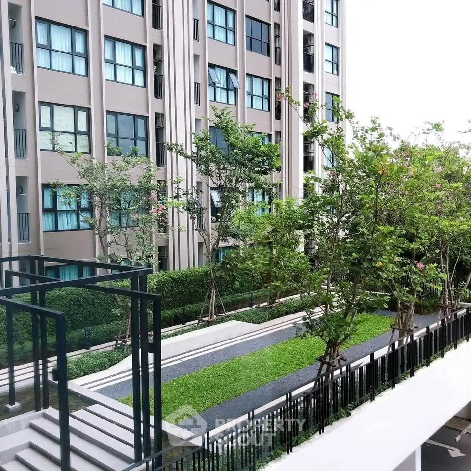 Modern apartment building with lush landscaped garden and sleek architectural design.