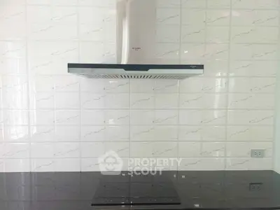Modern kitchen with sleek induction cooktop and stylish range hood.