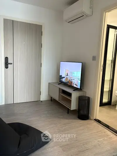 Modern living room with sleek TV setup and air conditioning, adjacent to a bathroom.