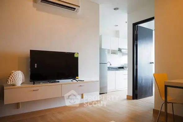 Modern living room with wall-mounted TV and view into sleek kitchen