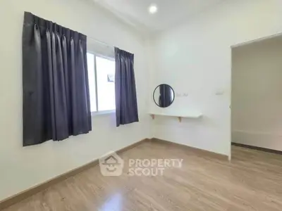 Bright empty room with wooden flooring and a round mirror, ideal for customization.