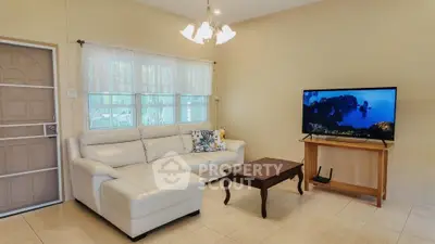 Cozy living room with white sectional sofa and flat-screen TV, perfect for relaxation.