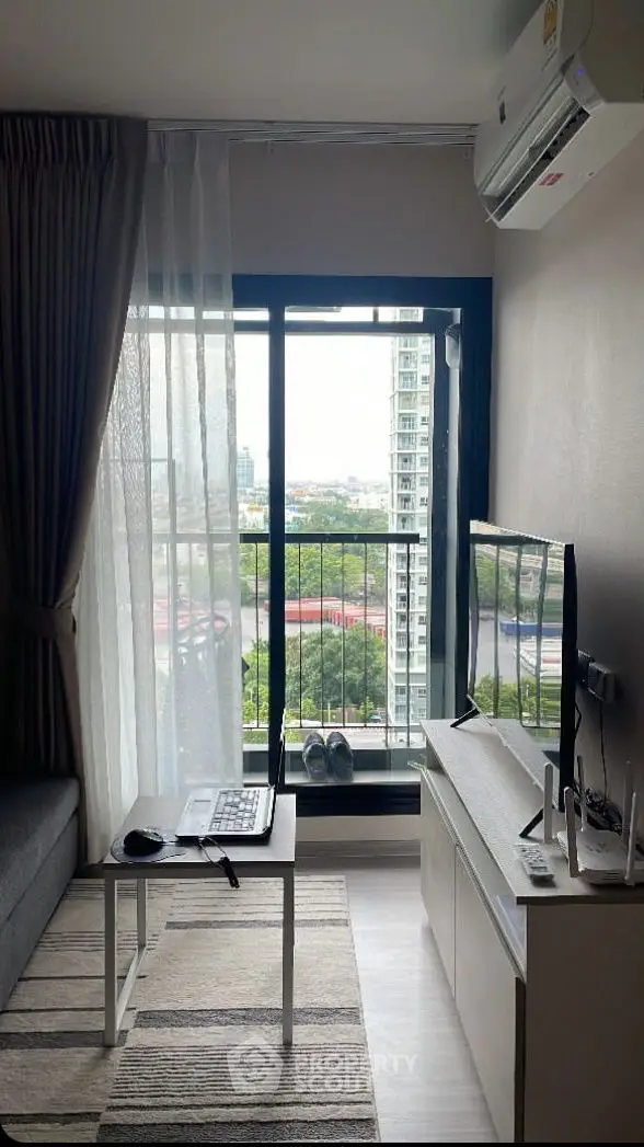 Modern living room with city view, featuring sleek furniture and large window for natural light.