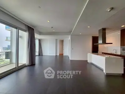 Spacious modern living room with open kitchen and large windows offering city views.