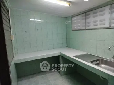 Spacious tiled kitchen with ample counter space and stainless steel sink, perfect for culinary enthusiasts.