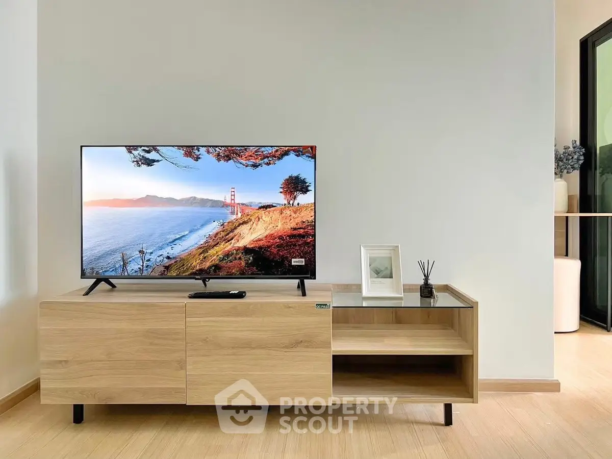 Modern living room with sleek wooden TV stand and flat-screen TV displaying scenic view.