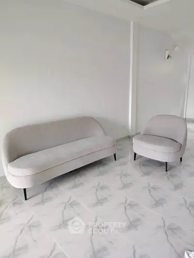 Modern minimalist living room with stylish sofa and armchair on elegant marble flooring.