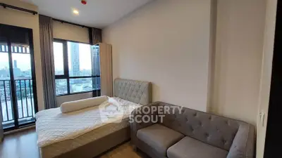 Modern bedroom with city view, featuring a cozy bed and stylish sofa, perfect for urban living.