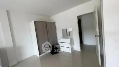 Spacious bedroom with modern wardrobe and sleek dresser in minimalist design.