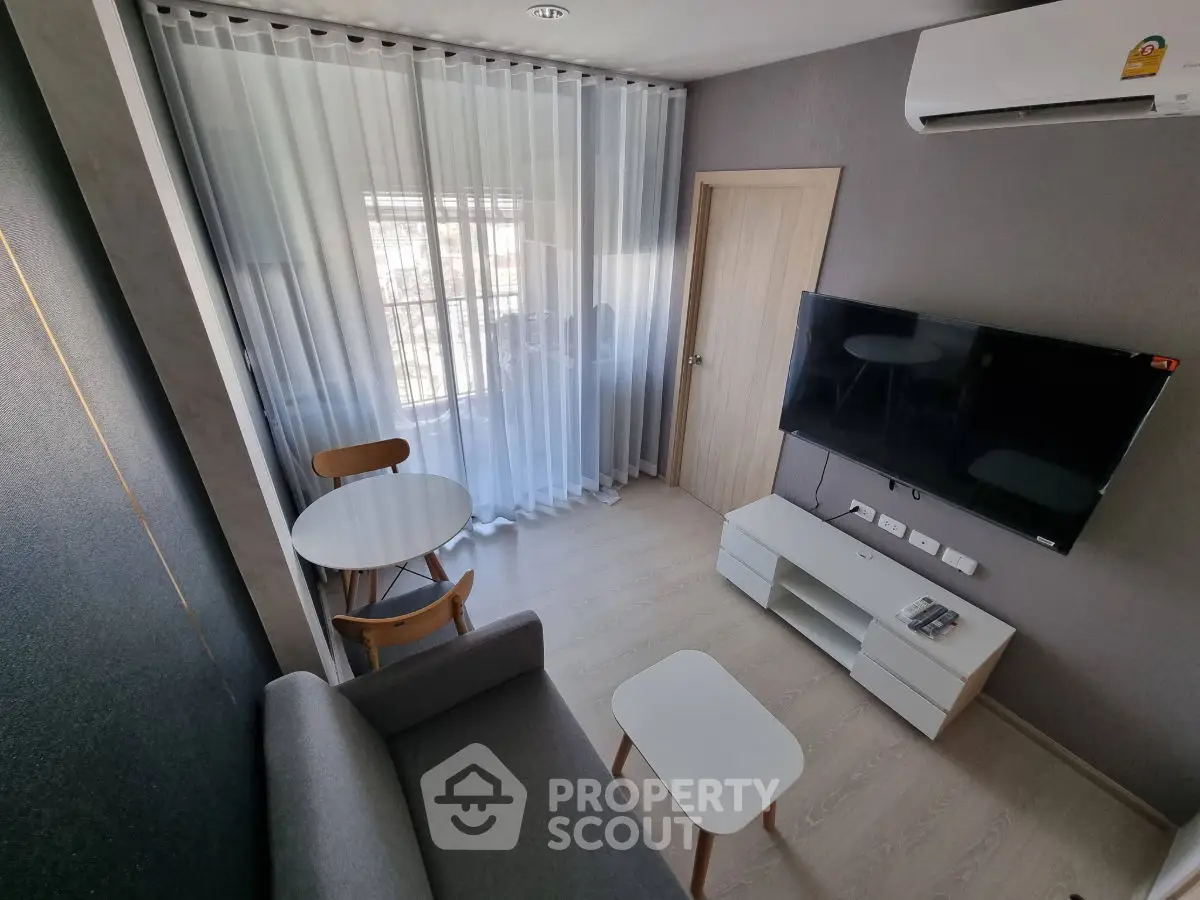 Modern living room with sleek furniture and wall-mounted TV, featuring a cozy seating area and natural light.