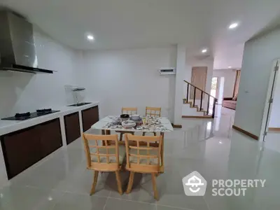 Modern open kitchen with dining area and sleek staircase in a spacious home