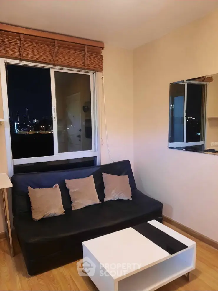 Cozy living room with city view, featuring a sleek black sofa and modern decor.
