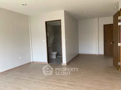 Spacious unfurnished room with wooden flooring and attached bathroom, ideal for customization.