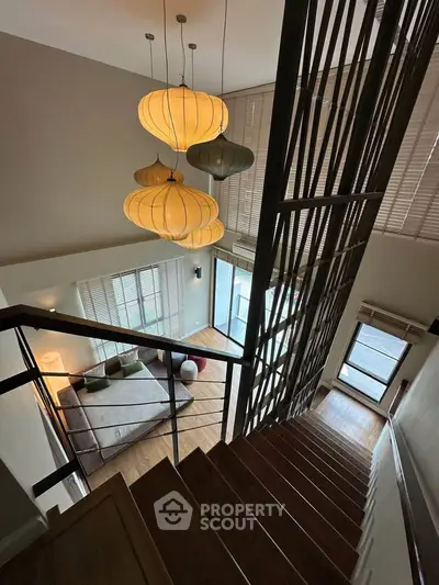 Stunning modern duplex with elegant staircase and stylish lighting, offering a spacious and inviting living area.