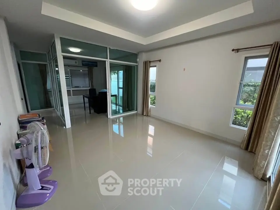 Spacious living room with glass partition and garden view, ideal for modern living.