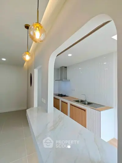Modern kitchen with open layout and elegant lighting, featuring a gas stove and sleek countertops.
