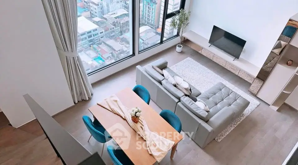Modern living room with large windows and stylish furniture offering city views