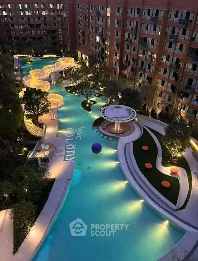 Luxurious apartment complex with illuminated pool and modern landscaping at dusk.