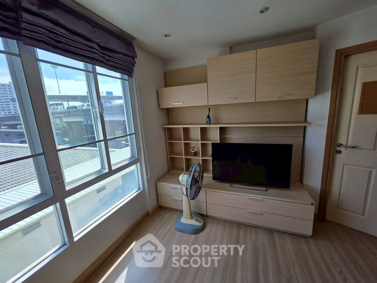 Modern living room with large windows and built-in wooden entertainment unit.