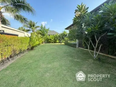 Spacious tropical garden with lush greenery and palm trees, perfect for outdoor relaxation and entertainment.