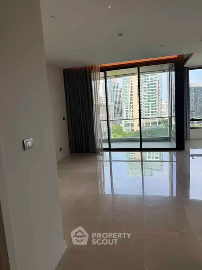 Spacious modern living room with large windows offering city views in a high-rise apartment.