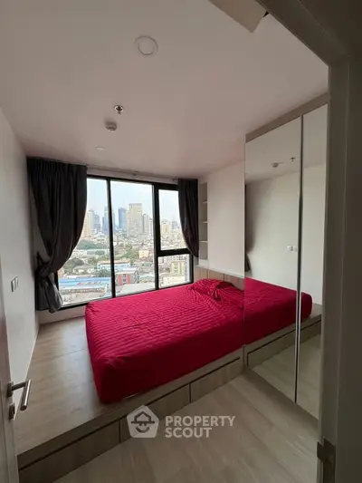 Modern bedroom with city view and red bedding in high-rise apartment
