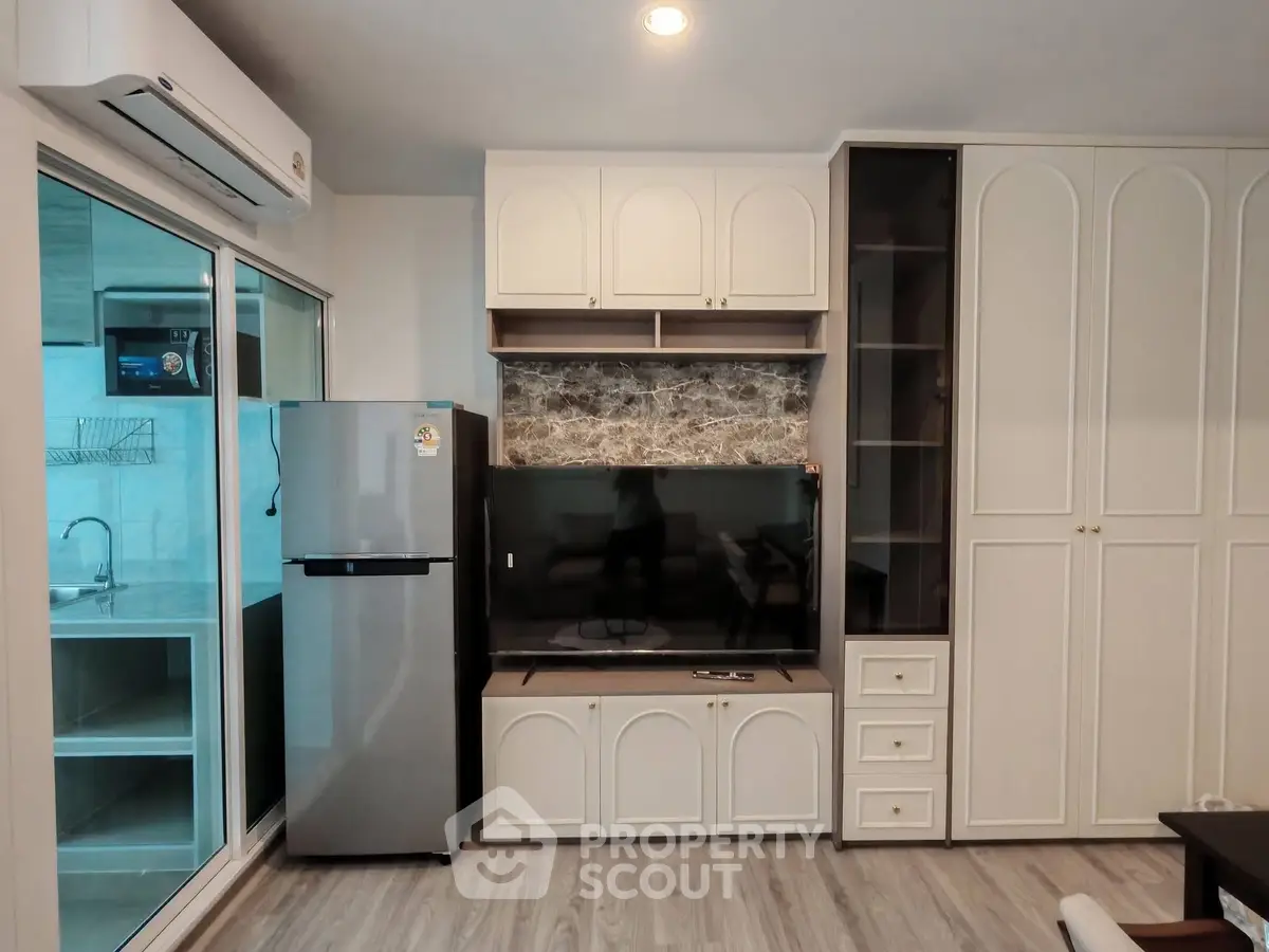 Modern living room with built-in cabinets and sleek appliances in a stylish apartment.