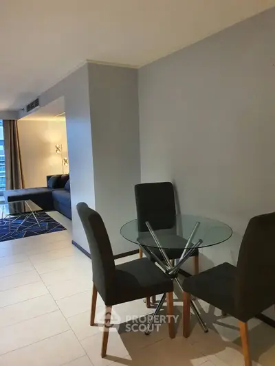 Modern living room with glass dining table and stylish seating in a contemporary apartment.