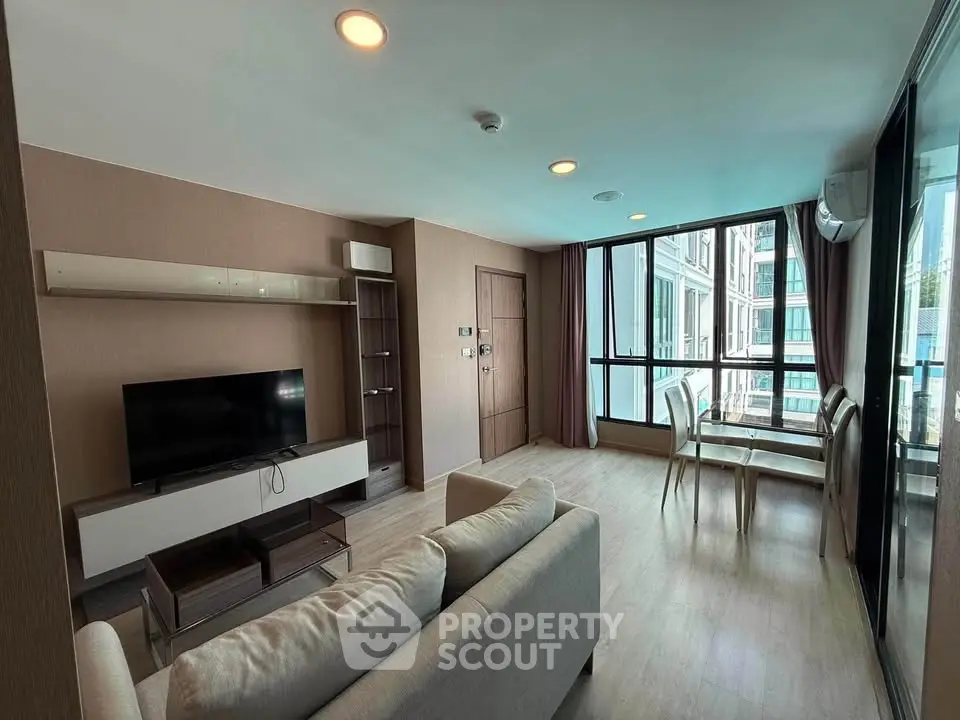 Spacious modern living room with large windows and dining area in a stylish apartment.