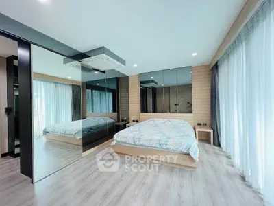 Modern bedroom with mirrored walls and large windows in a stylish apartment.