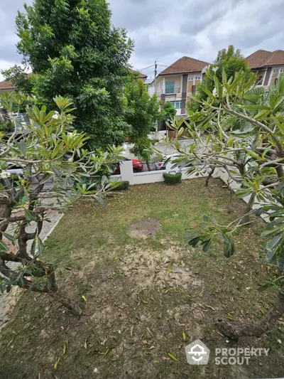 Charming garden view in suburban residential area with lush greenery and modern houses.