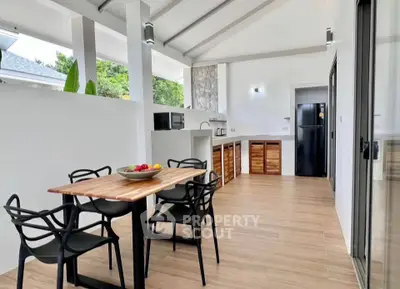 Modern open kitchen with sleek design and dining area, featuring wooden cabinets and contemporary furniture.